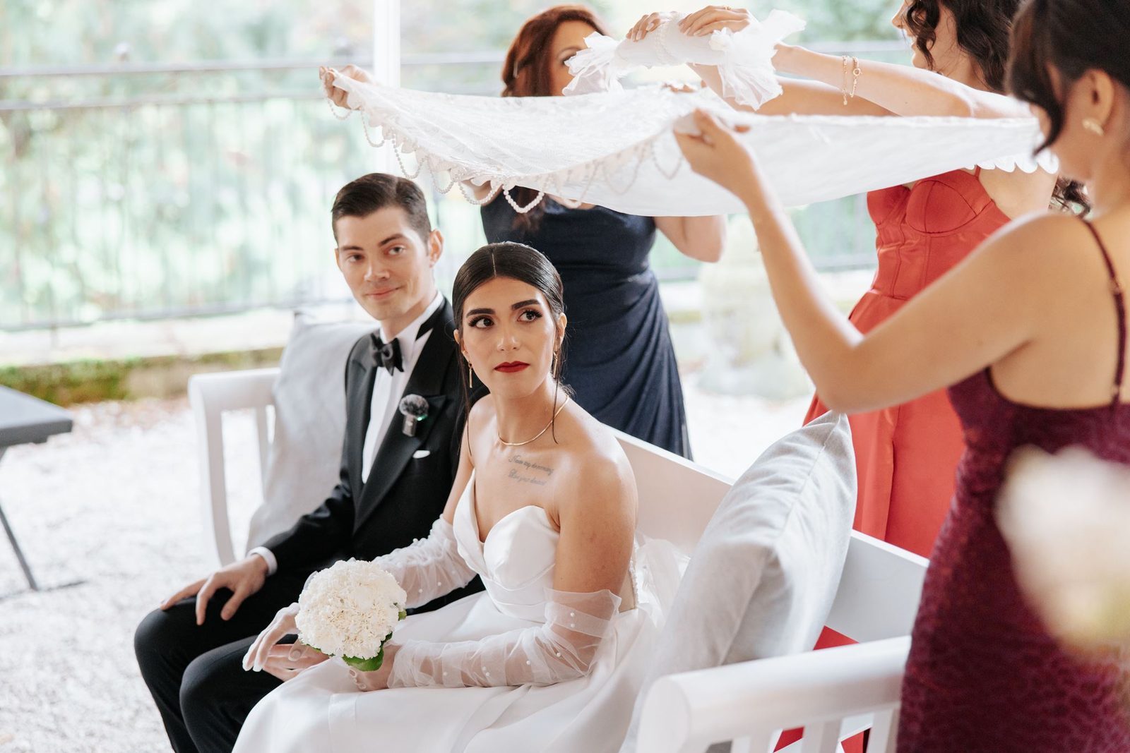 Persian wedding Aghd ceremony — bride and groom seated under traditional silk cloth held by friends