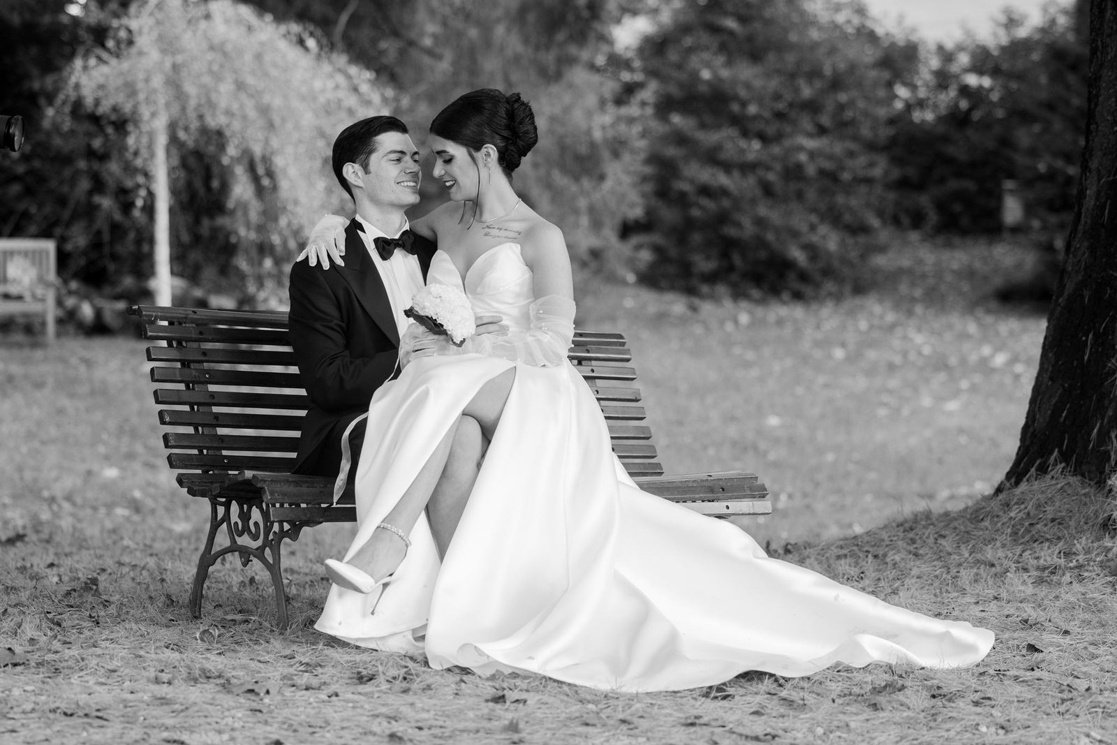 Persian bride and groom sitting on a vintage bench in a venue garden — black and white